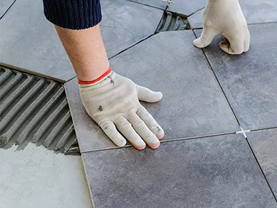 Carreleur en train de poser une dalle de carrelage gris